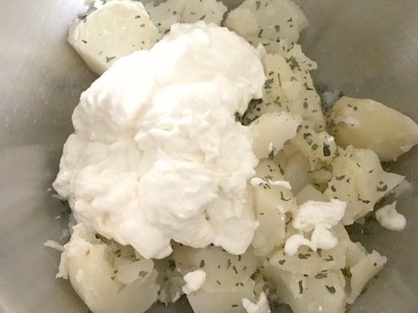 Cream cheese on mashed potatoes in a bowl.