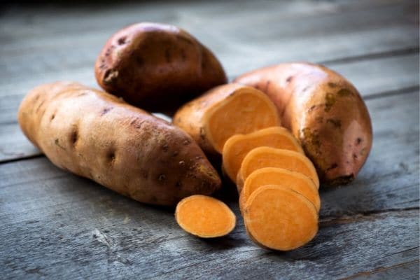 Sweet potatoes sliced and whole on a board