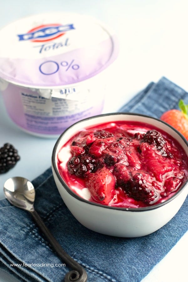 A container of FAGE yogurt next to a mixed berry yogurt bowl.