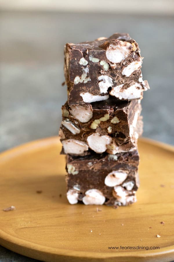 A stack of peppermint rocky road fudge pieces on a wooden plate.