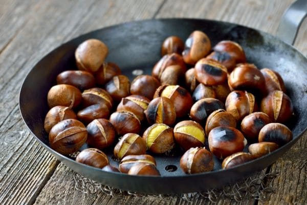 Hot chestnuts roasting in a pan.