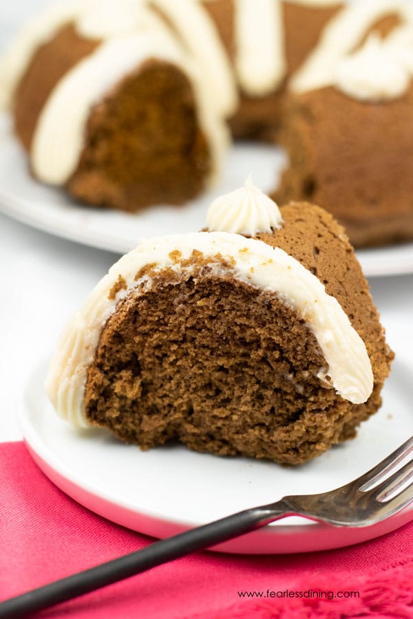 A slice of gluten free gingerbread bundt cake with cream cheese frosting on a plate.