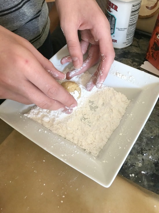 Rolling the eggnog cookie dough balls in powdered sugar