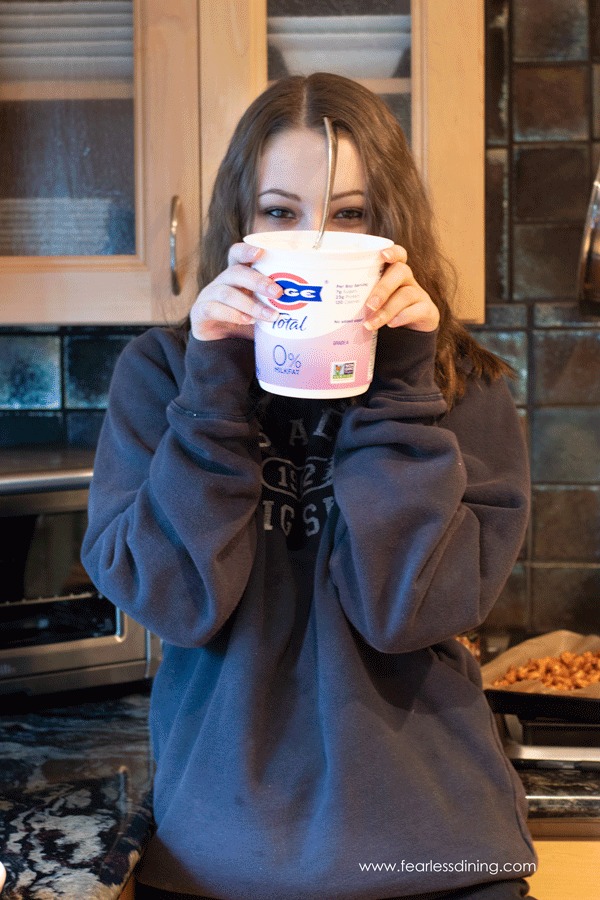 A photo of someone holding up a container of Greek yogurt.