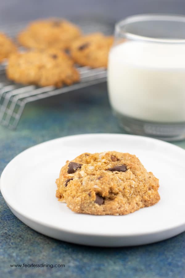an almond flour cookie on a plate next to a glass of milk