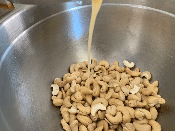 Pouring honey and melted butter into the cashews.