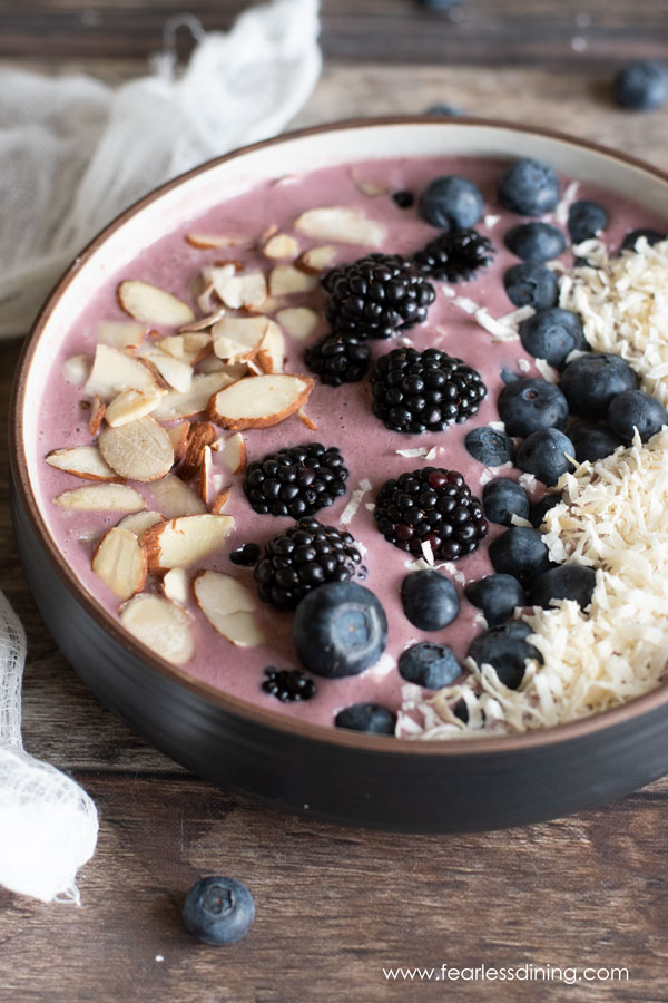 Acai bowl topped with slivered almonds, blackberries, blueberries and coconut.