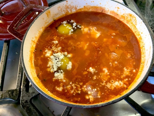 Adding feta cheese to the cooking tomatoes.