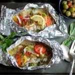 Cooked red snapper and veggies in foil packets.