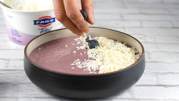 Adding blueberries to the smoothie bowl.