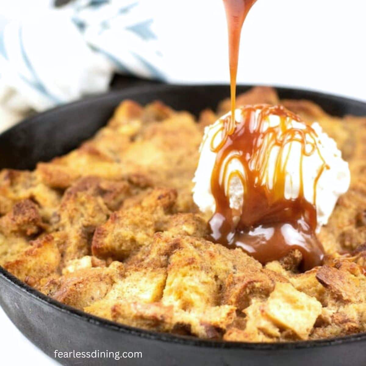 Topping the banana bread pudding with vanilla ice cream and caramel sauce.