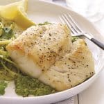 Pan seared cod on a plate over minted pea puree.