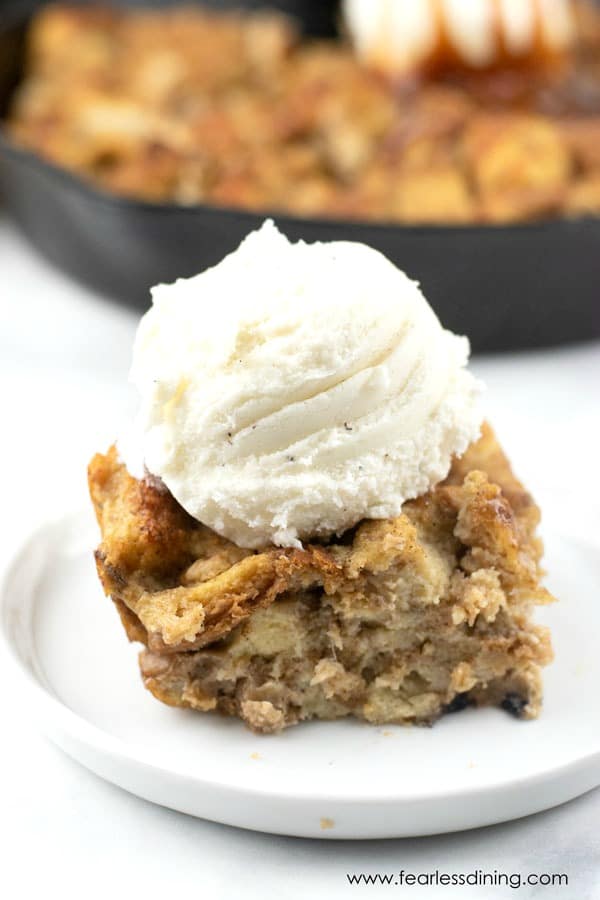 A slice of gluten free banana bread pudding on a plate with vanilla ice cream on top.