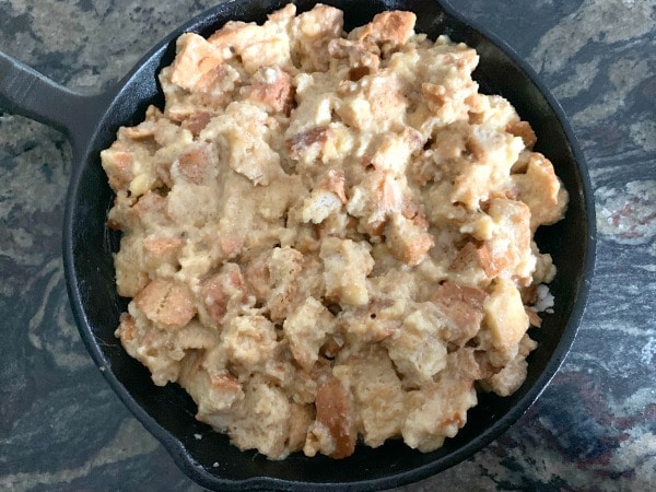 The wet bread cubes in a cast iron skillet ready to bake.