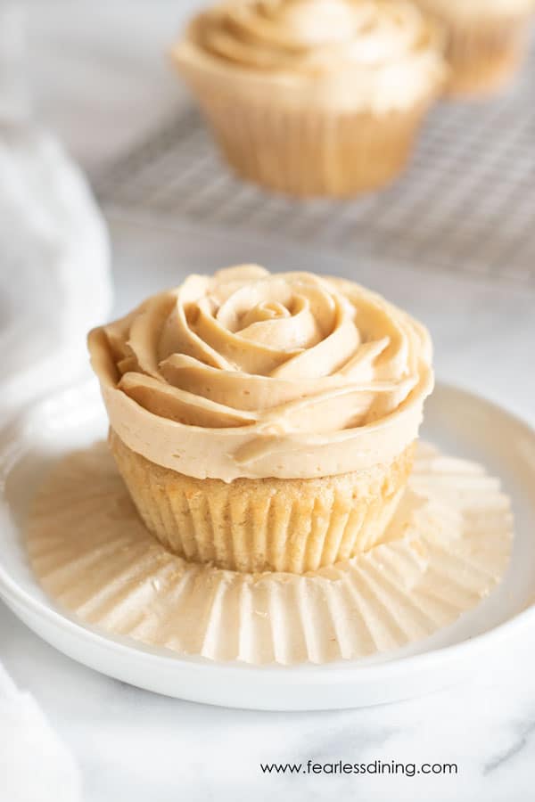 A gluten free caramel cupcake on a plate with the paper liner peeled.