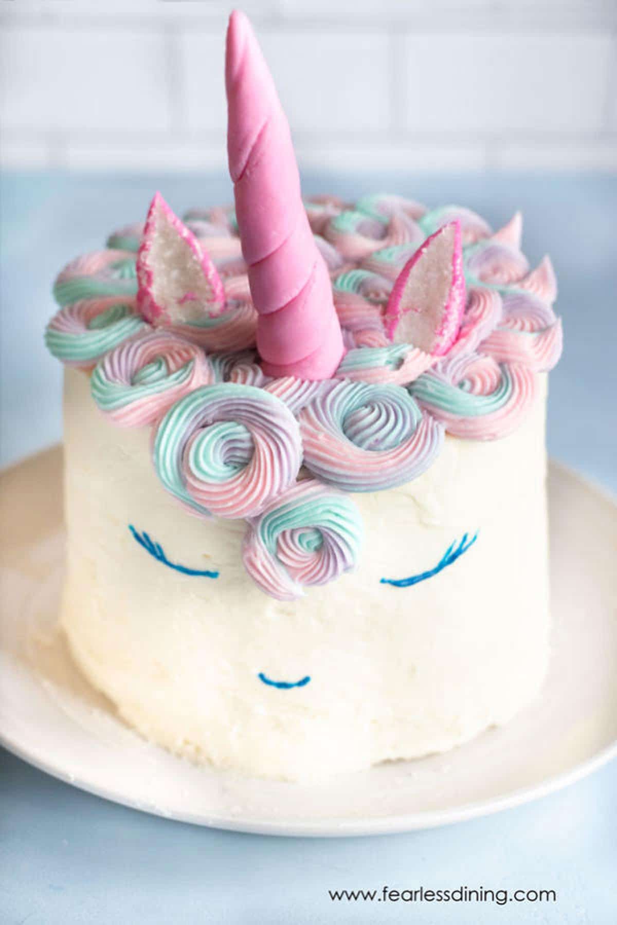 A decorated unicorn cake on a white plate.