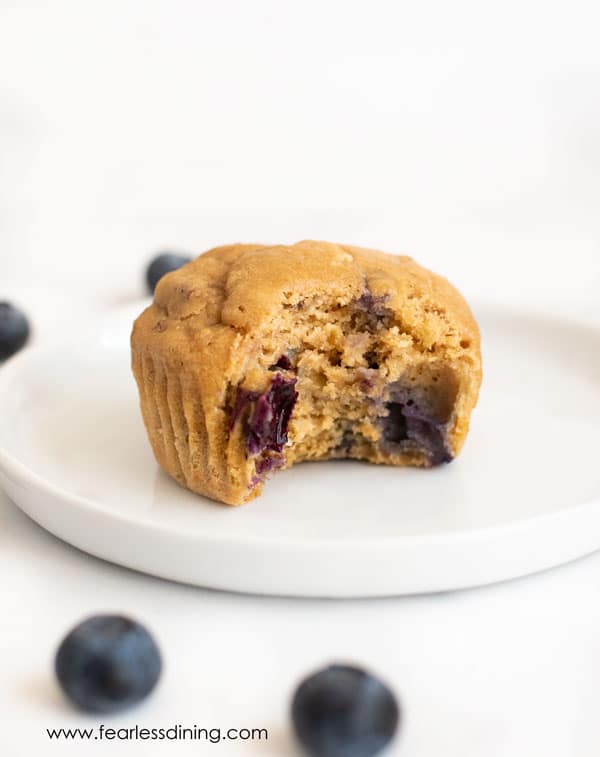 A blueberry protein muffin with a bite taken out on a plate.