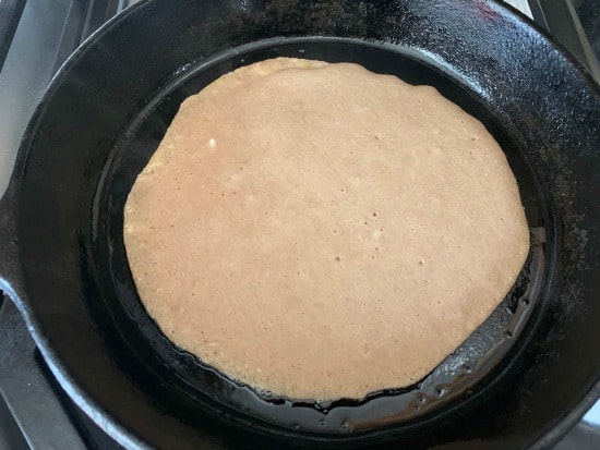 The  flipped crepe in a skillet.