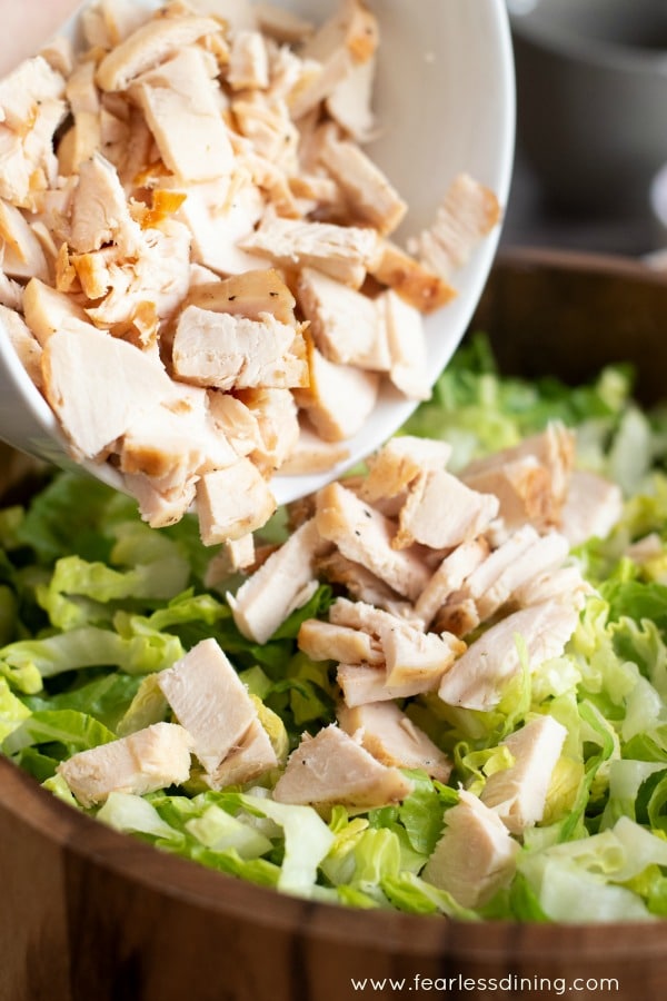 Adding chopped chicken to the salad.
