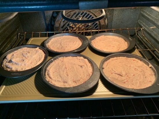 Mini cake pans with strawberry cake batter in the oven.