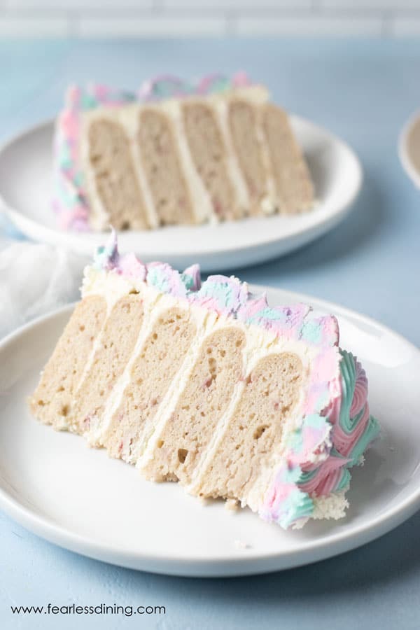 Two slices of unicorn cake on white plates.