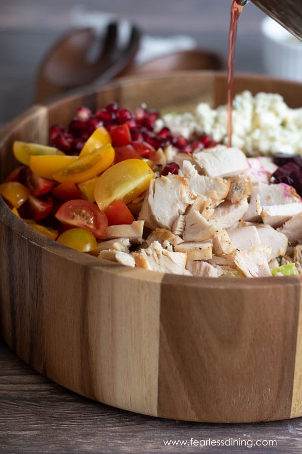 Pouring salad dressing onto the chopped salad.