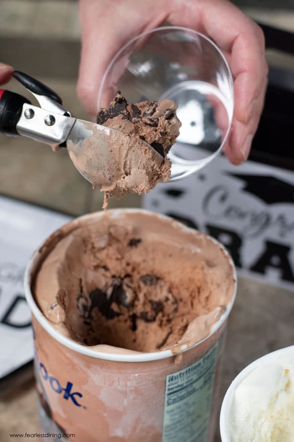 Scooping chocolate ice cream into a cup.