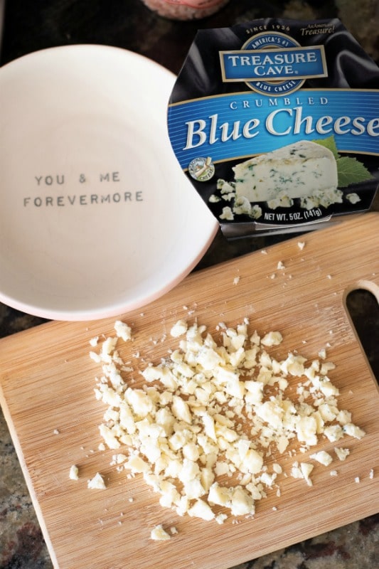 Blue cheese being chopped on a cutting board.