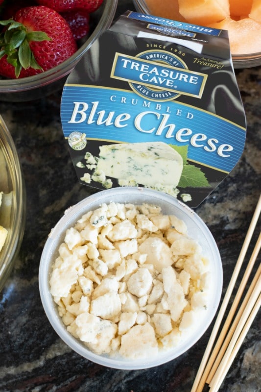 The top view of the blue cheese with cut fruit and skewers.