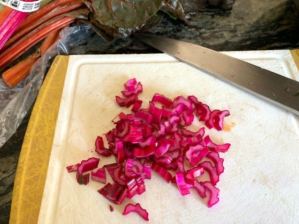 Chopped hot pink Swiss chard stems on a cutting board.