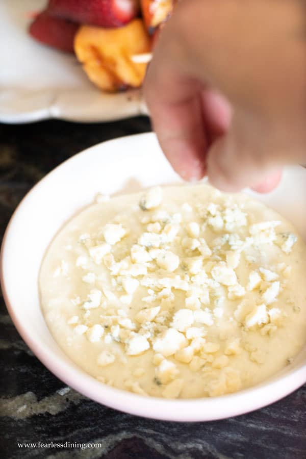 Dropping blue cheese crumbles in the blue cheese dip.