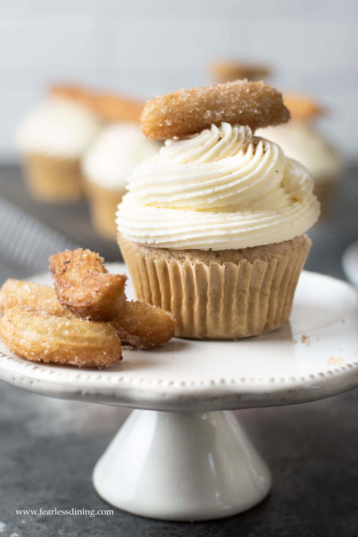 A churro cupcake on a cupcake stand.