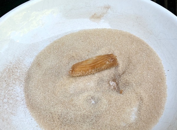 a churro in a bowl of sugar and cinnamon