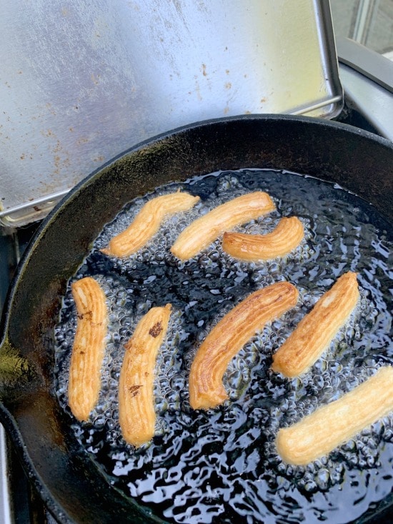 Gluten free churros cooking in hot oil.