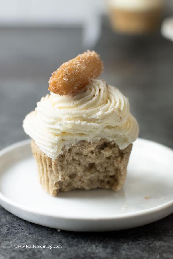 A gluten free churros cupcake with a bite taken out.