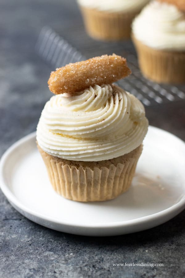 A gluten free churros cupcake with a mini churro on top.