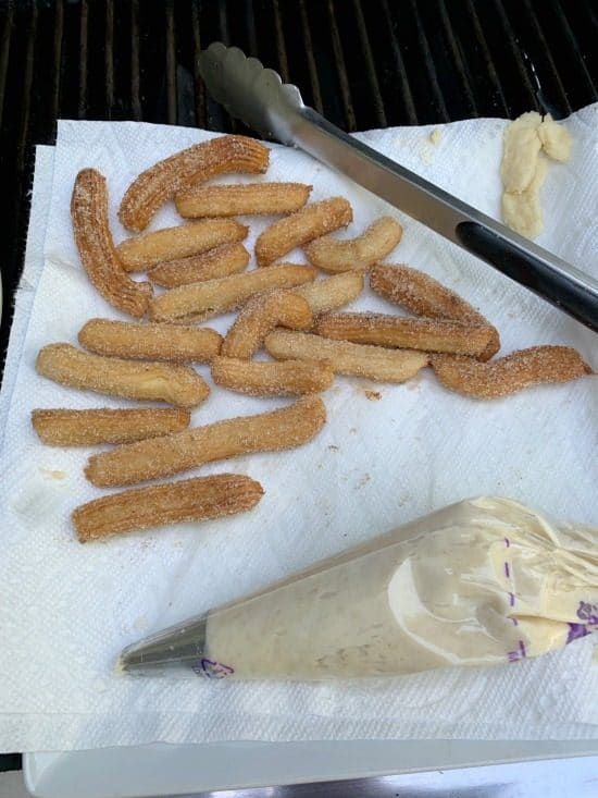 The churros and pastry bag of churro dough on a plate.