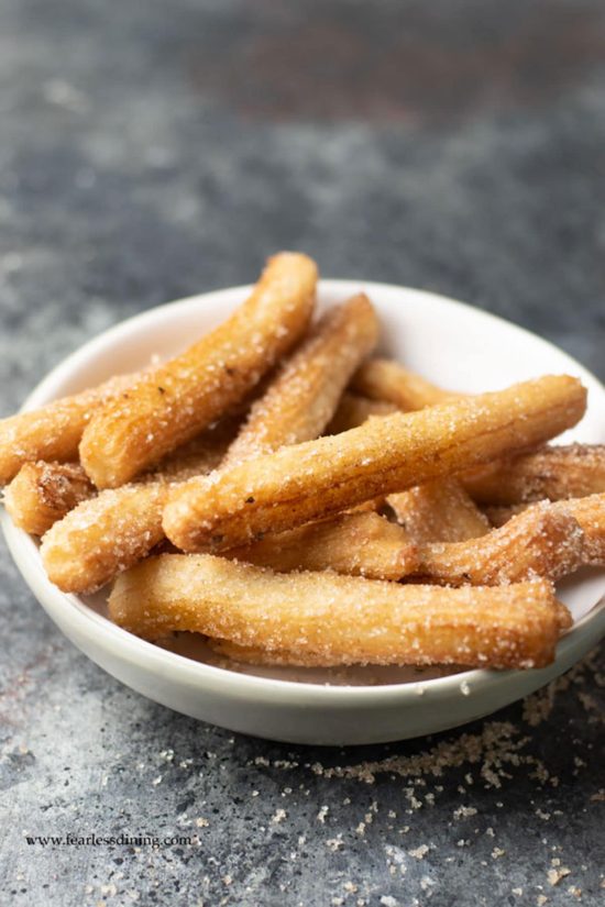 A bowl full of fried churros on the counter.