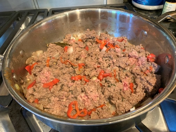 The ground beef, onion, and pepper cooked in a pan.
