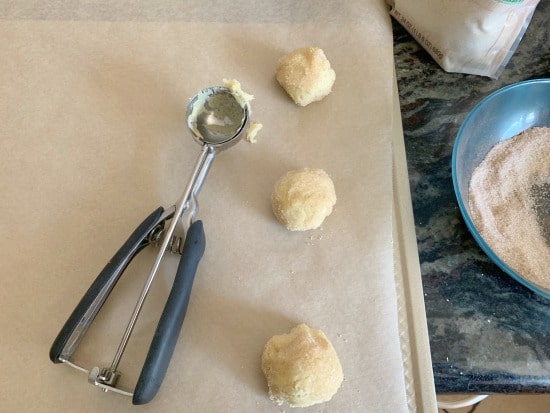 Cookie dough on a baking sheet next to a cookie scoop.