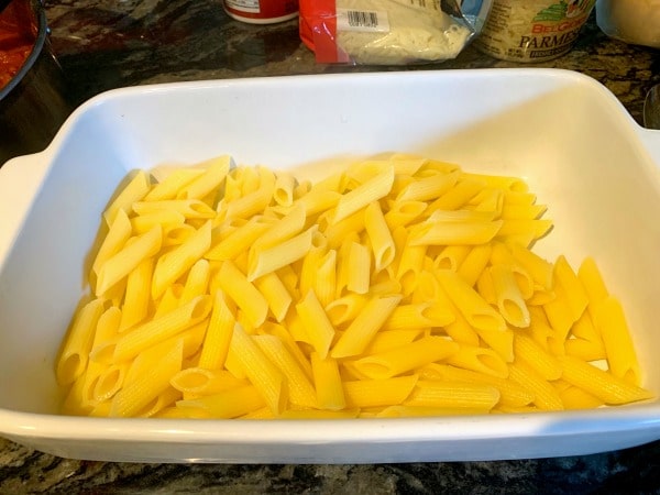 A layer of cooked gluten free ziti in a casserole dish.