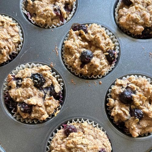 Baked blueberry oat muffins in a muffin tin.