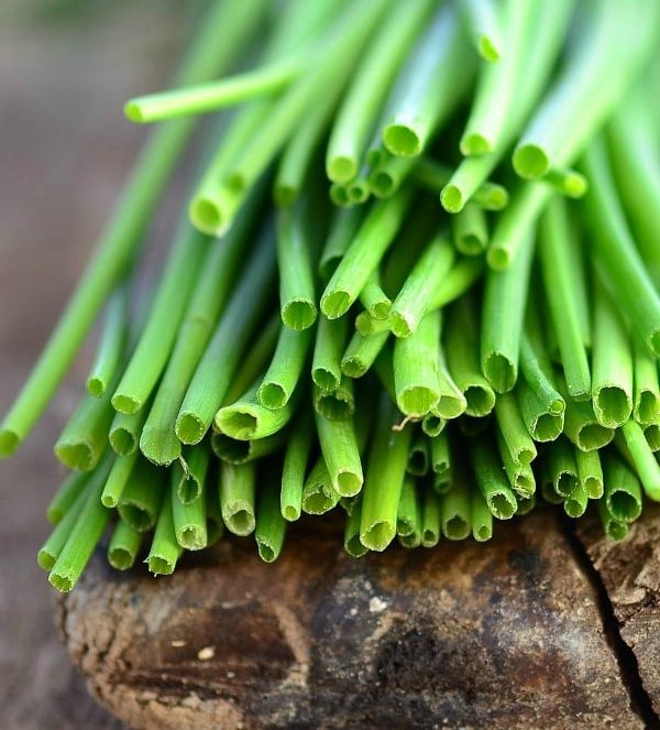 Fresh chives on an an old wooden cutting board.