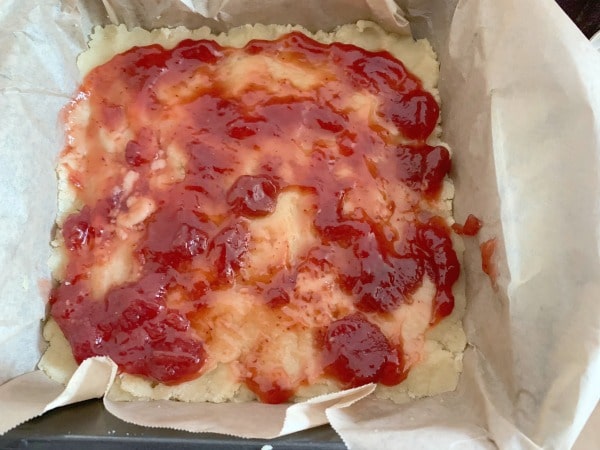 The strawberry jam spread on the crust.