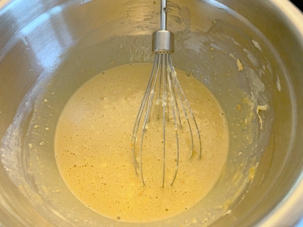 The wet donut ingredients in a bowl with a whisk.