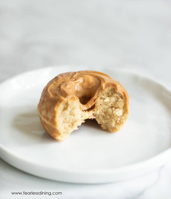 A donut on a white plate with a bite taken out.