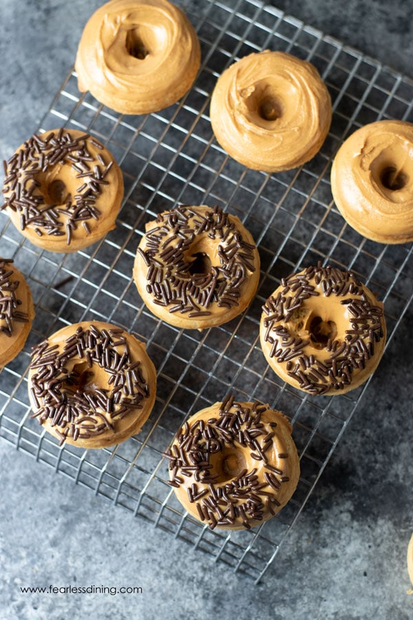 A rack with mini gluten free peanut butter donuts. Some have chocolate sprinkles.