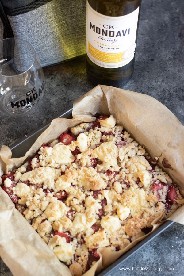 A bottle of chardonnay next to a pan of strawberry bars.