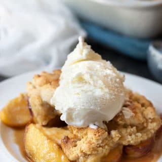 A serving of paleo peach cobbler topped with vanilla ice cream.