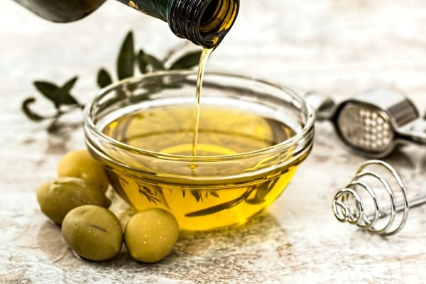 Pouring olive oil into a glass bowl.